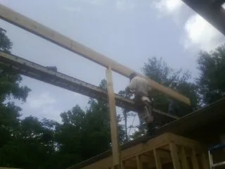 Carpenter setting a ridge beam over a new addition frame — Ice Dam Removal by Roofing Brothers in New City