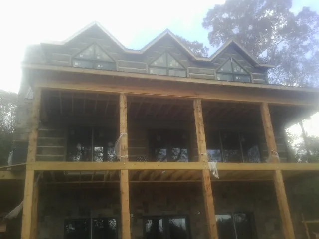 Dormers and porch framing on a large log home under construction — Roof Coating work by our crew in New City