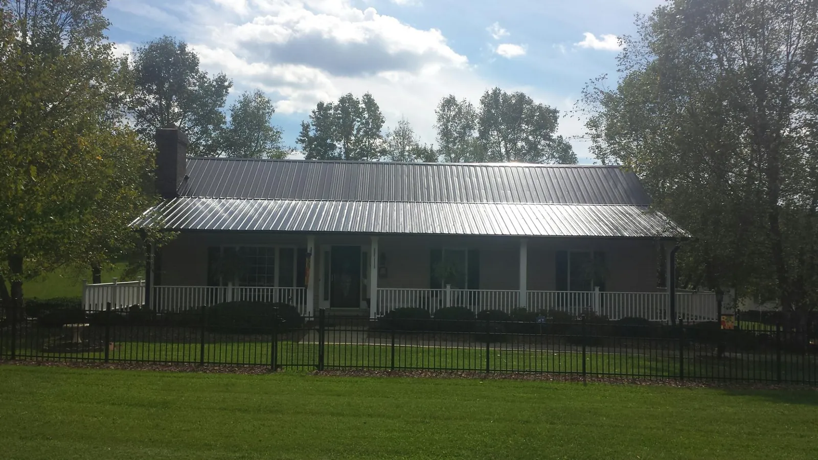 Gray metal roof on a brick ranch with a full width front porch — Gutter Guard Installation work by our crew in New City