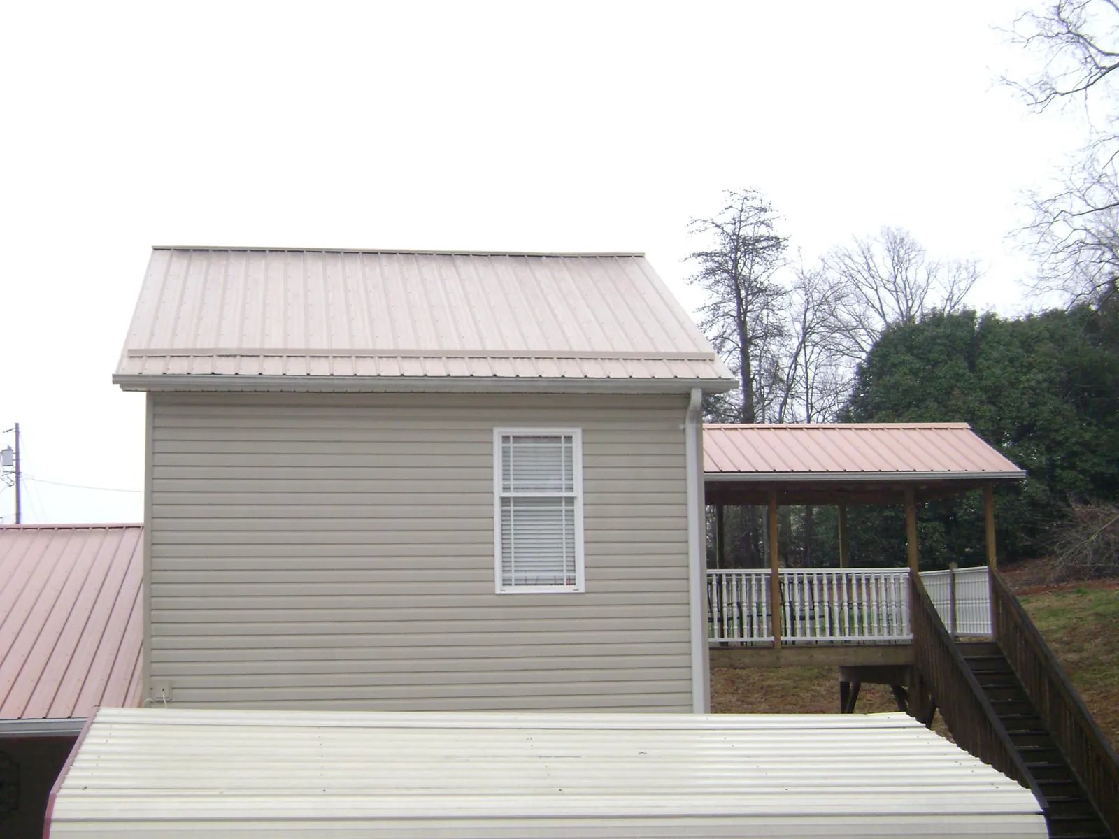 Tan metal roofs on a two story addition and attached porch, from a Roof Replacement job in New City