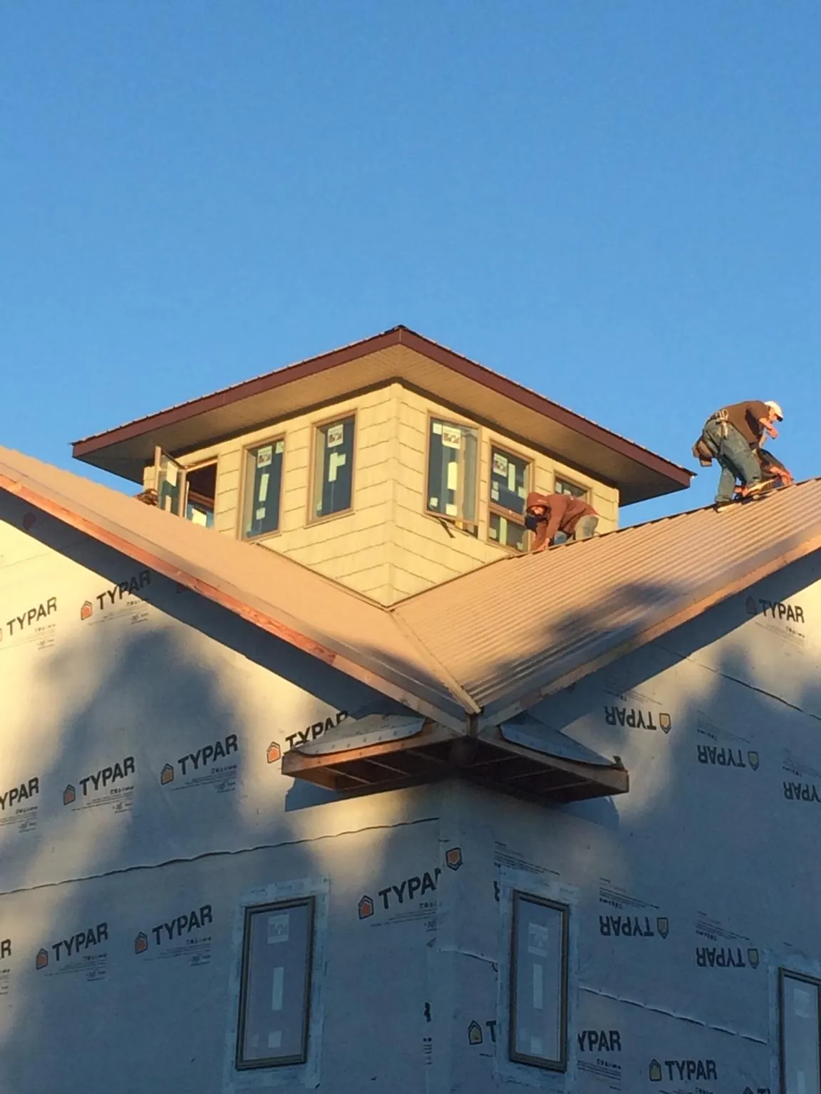 Roofers working around a rooftop cupola on a new metal roof at sunset — Roof Waterproofing in New City by Roofing Brothers